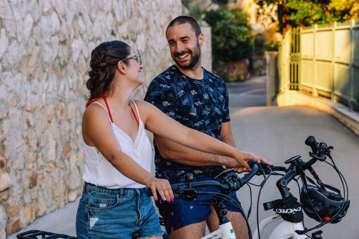 Visitors smiling beside their e-bikes on a Dubrovnik street.